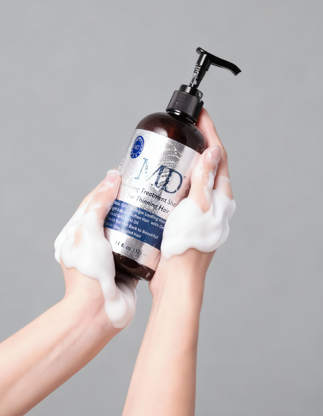 Hand holding MD® Revitalizing Treatment Shampoo bottle – sulfate-free DHT-blocking formula for thinning hair and scalp health, from the MD Hair system
