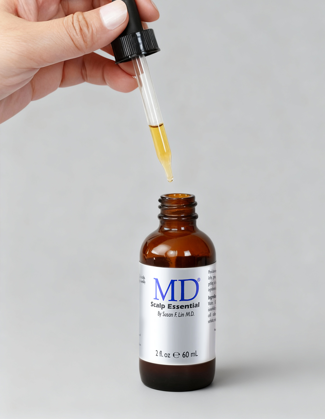 Person holding dropper of MD Scalp Essential serum for anti-itch, oily scalp relief and healthy hair support in the MD Hair collection