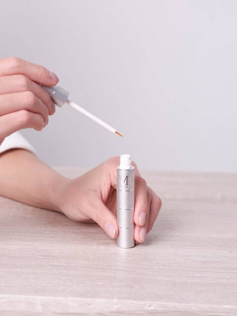 Hand holding MD Lash Factor 3-Month precision-tip applicator for easy, targeted lash serum application